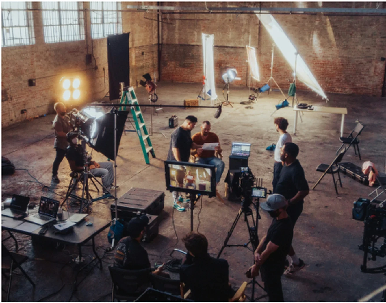 A large-format production set up in a warehouse studio, crew working around lighting rigs and monitors.