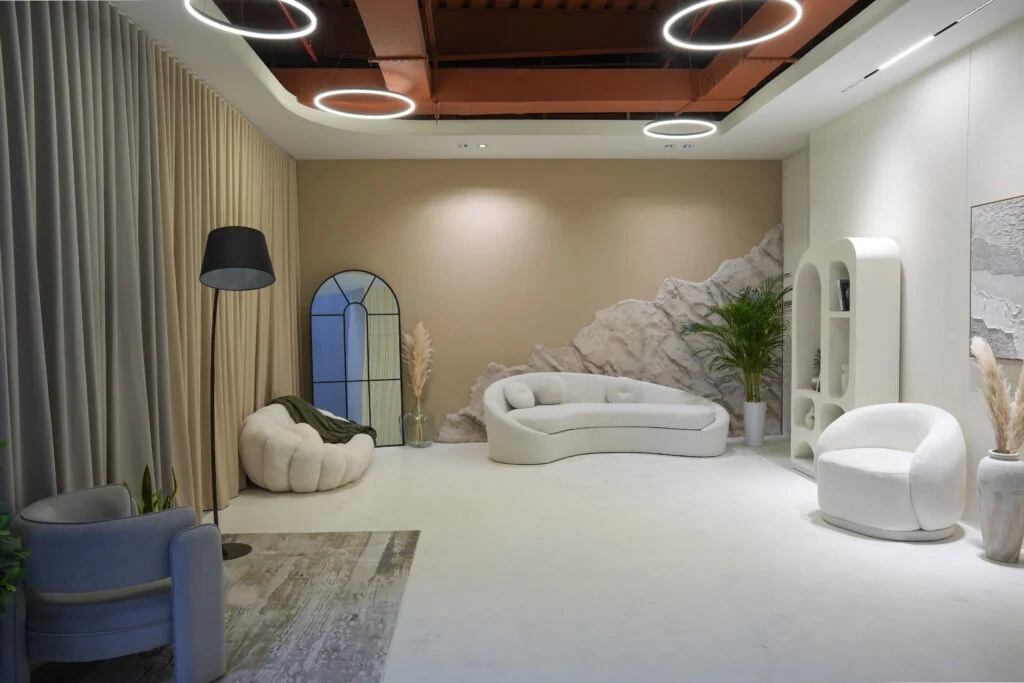 The interior studio: a curved bouclé sofa, arched window, plaster feature wall and floor lamp.